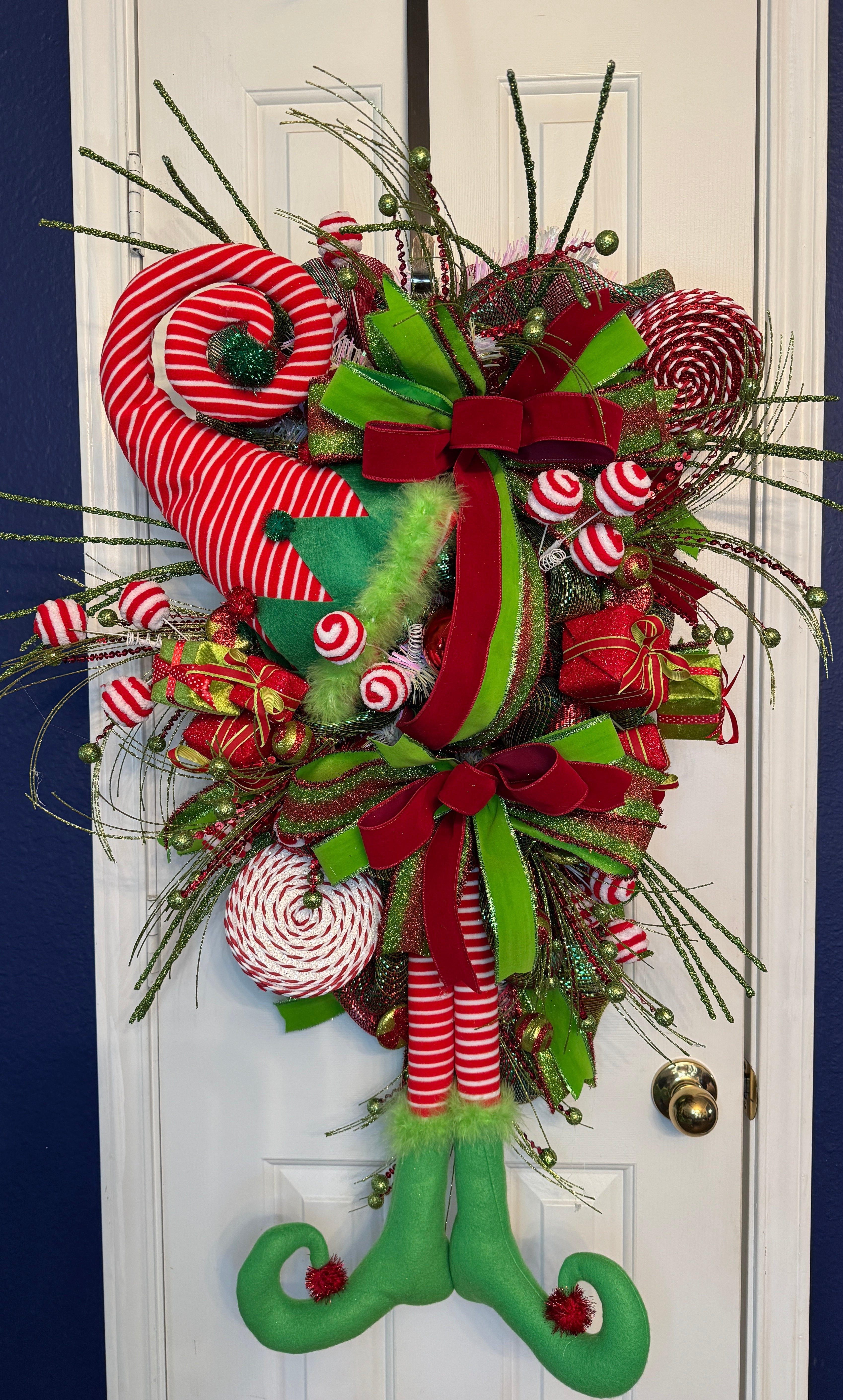 Large swag christmas Wreath in red and green with beautiful ribbons on red, green, red/white stripes and large imbedded ornaments and attachments